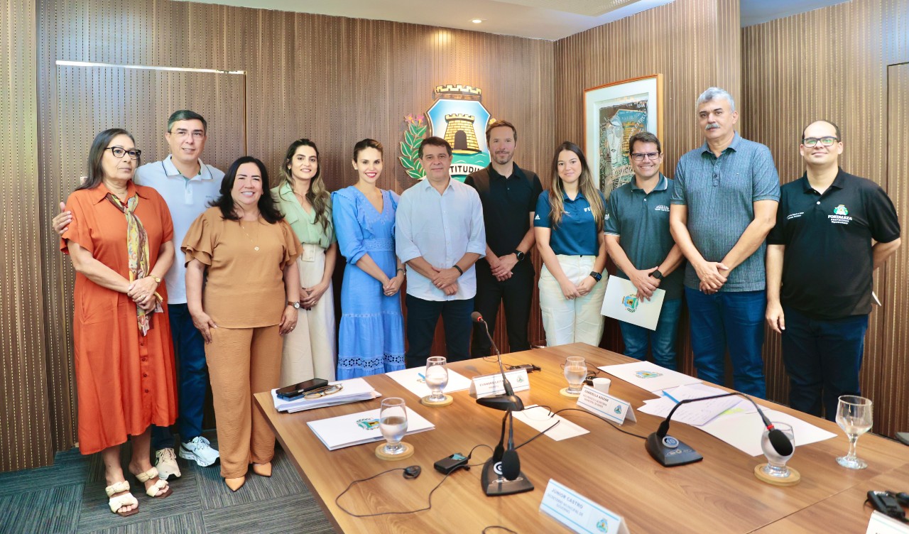 grupo de pessoas posa para a foto na sala de reunião do paço